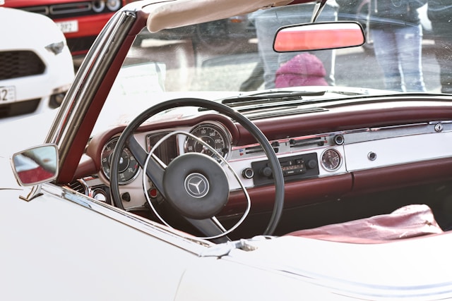 Habitacle raffiné d’une Mercedes Pagode W113 avec volant noir, instrumentation classique et intérieur rouge  des années 60.