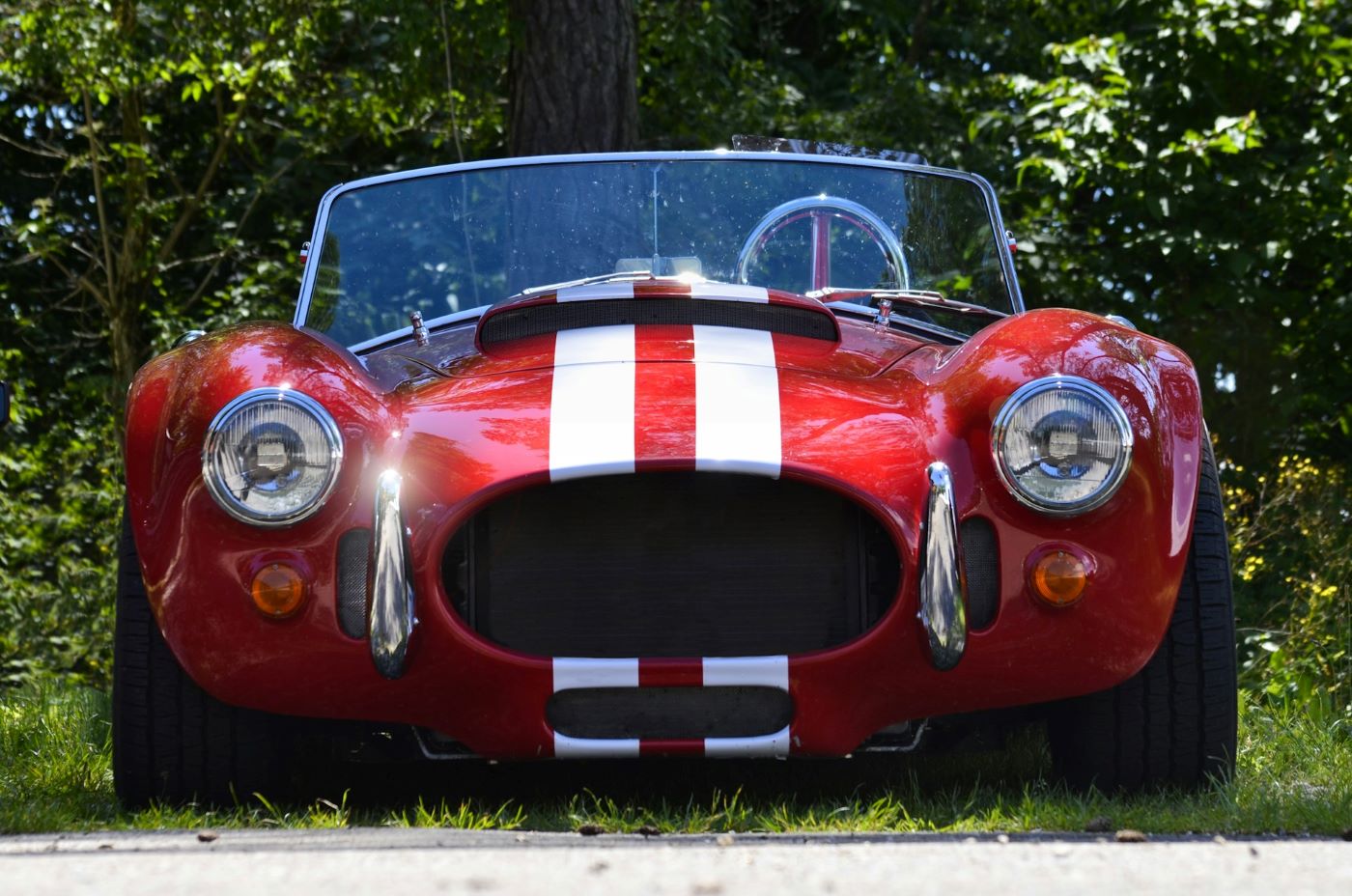 AC Cobra vue trois quarts avant, mettant en valeur ses ailes galbées, sa calandre caractéristique et les lignes qui ont fait sa réputation dans le monde entier.