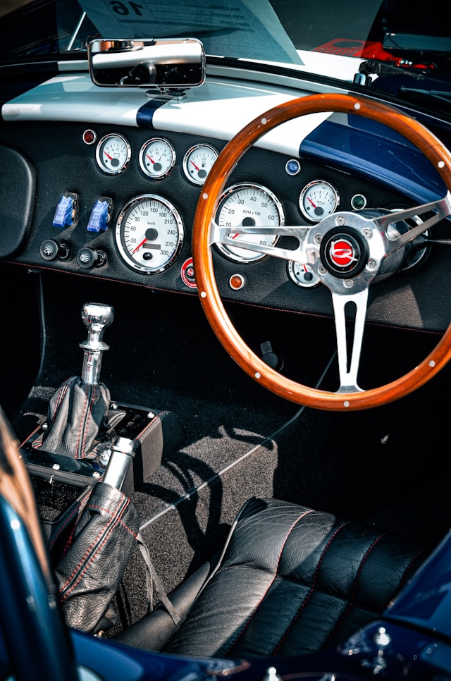 Habitacle d'AC Cobra avec instrumentation Smiths, volant bois et présentation minimaliste orientée vers les performances et le plaisir de conduite.