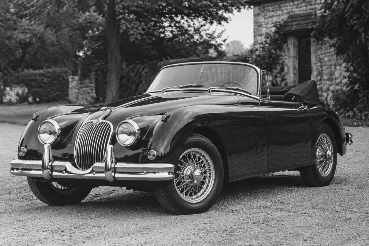 Photographie en noir et blanc d'une Jaguar XK150 Cabriolet, rappelant les clichés publicitaires des années 1950.
