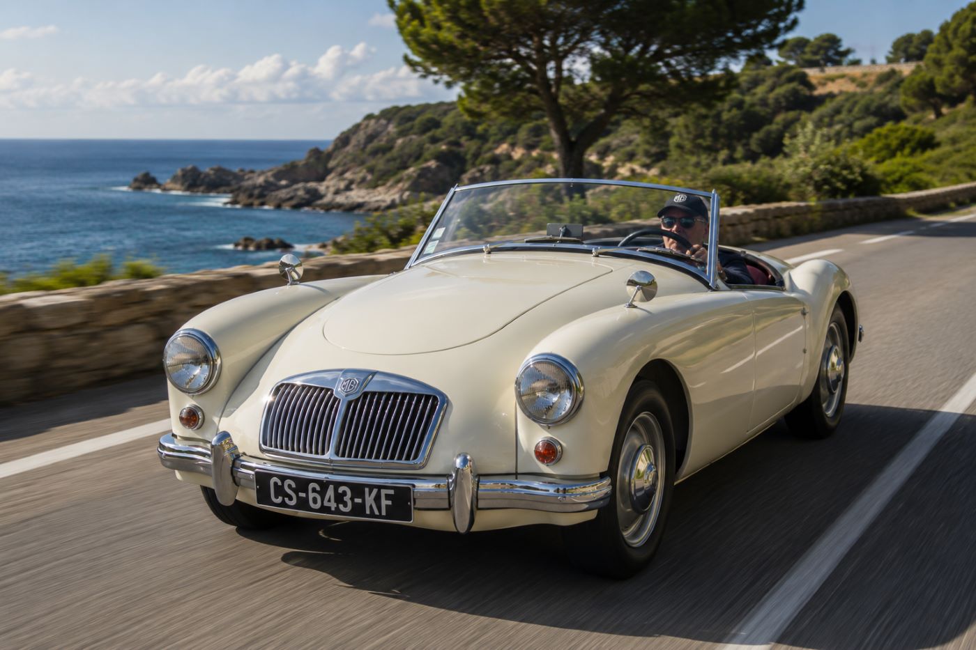 MGA crème vue de trois quarts avant sur une route de campagne, mettant en valeur les lignes élégantes du roadster britannique des années 1950.