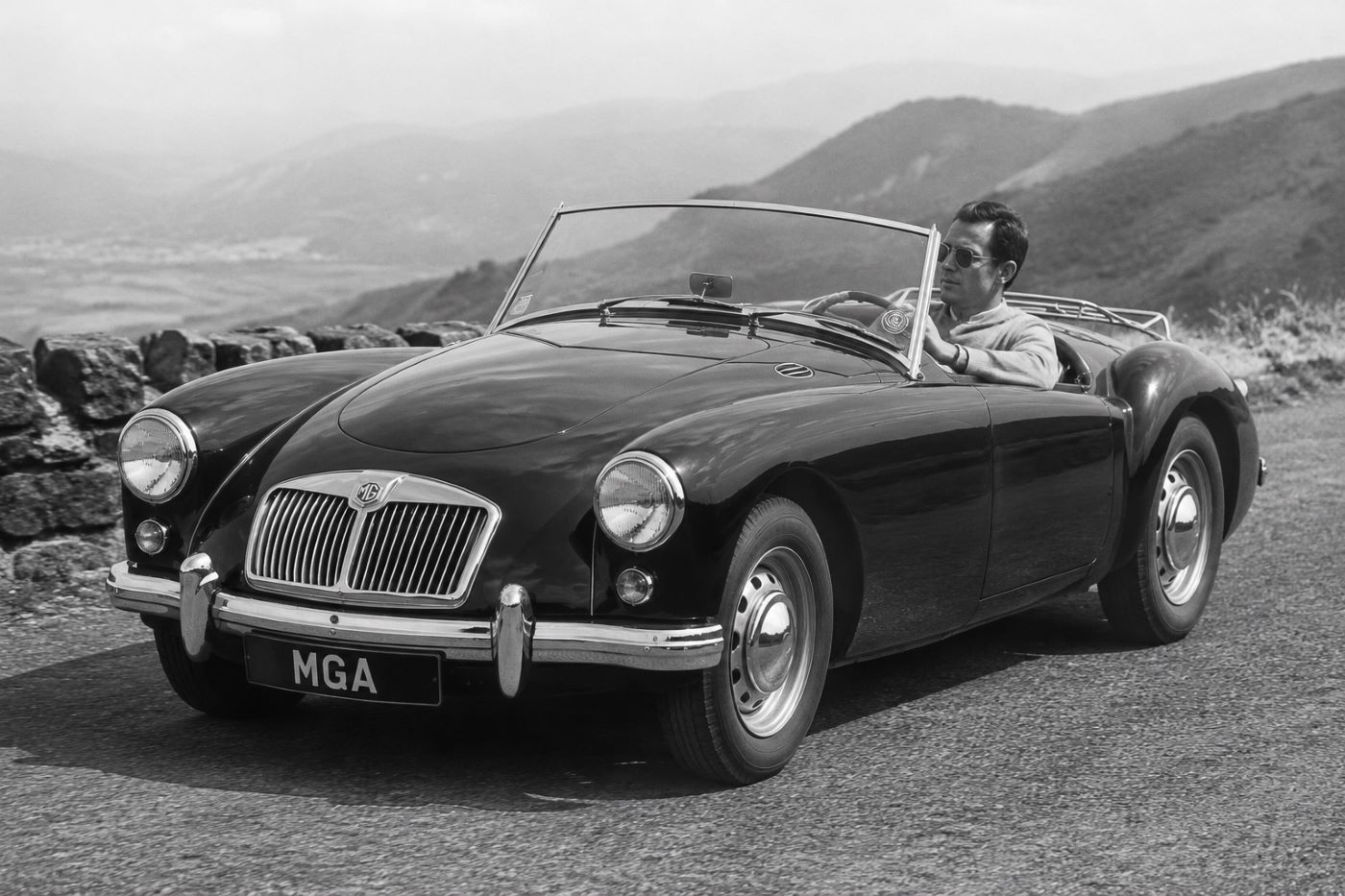 Photographie en noir et blanc d'une MGA des années 1950, évoquant les débuts du roadster britannique et son héritage automobile.