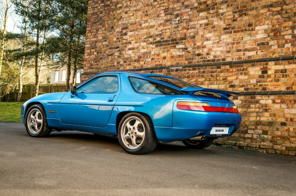 Vue arrière trois quarts d'une Porsche 928 de collection mettant en valeur son design emblématique et sa large poupe caractéristique.