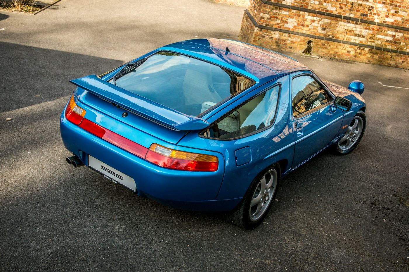 Vue aérienne d'une Porsche 928 de collection permettant d'apprécier les proportions équilibrées et le design unique de cette GT Porsche.