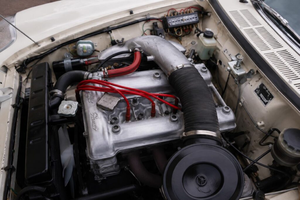 Moteur double arbre Alfa Romeo d'un Spider Duetto avec capot ouvert, illustrant la mécanique emblématique des Alfa Romeo classiques des années 1960.