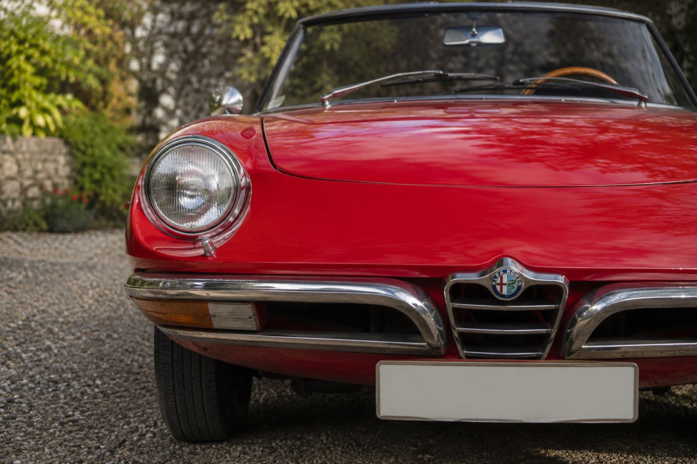 Gros plan sur la face avant d'un Alfa Romeo Spider Duetto, mettant en valeur la calandre, le phare rond et les lignes dessinées par Pininfarina.