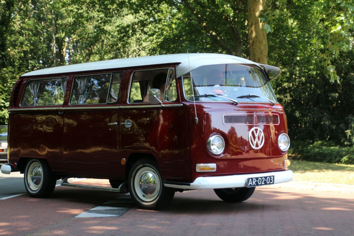 Volkswagen Combi T2 Bay Window rouge bordeaux de collection stationné en extérieur, version emblématique des années 1970 particulièrement recherchée par les passionnés de véhicules anciens.