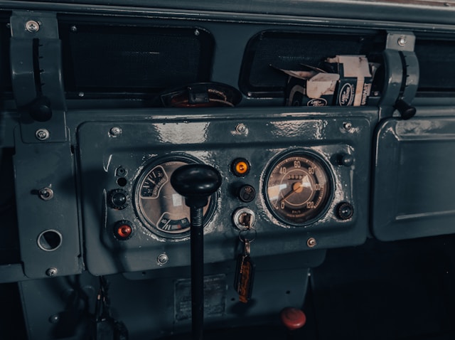 Habitacle d'origine d'un Land Rover Série avec tableau de bord minimaliste, commandes mécaniques et ambiance utilitaire authentique.