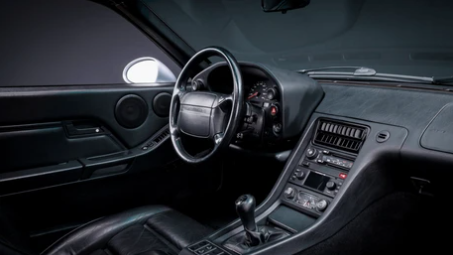 Intérieur de Porsche 928 avec tableau de bord orienté vers le conducteur, sièges confortables et ambiance typique des GT Porsche haut de gamme.