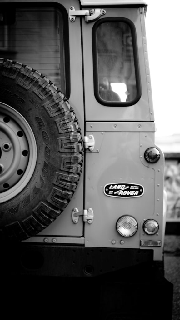 Vue arrière d'un Land Rover Série restauré mettant en valeur la carrosserie aluminium et les équipements caractéristiques du modèle.