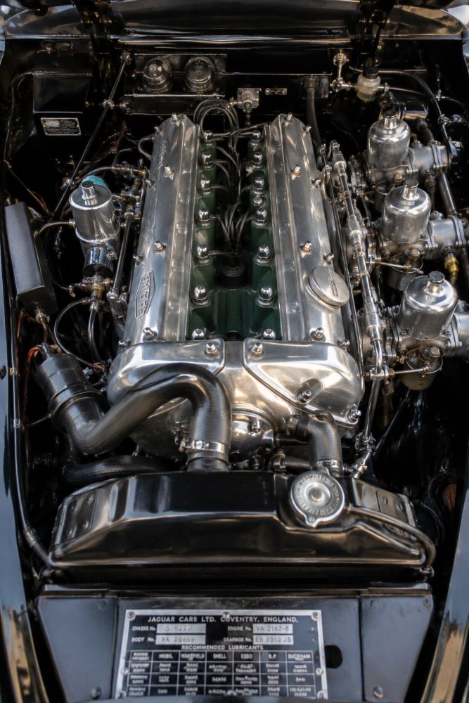 Moteur six cylindres XK d'une Jaguar XK150 avec capot ouvert, mettant en avant la mécanique emblématique des Jaguar classiques.