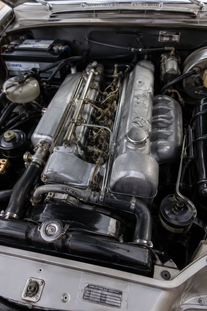 Gros plan du moteur six cylindres à injection mécanique d'une Mercedes W111 Coupé, réputé pour sa fiabilité, sa souplesse et sa longévité.
