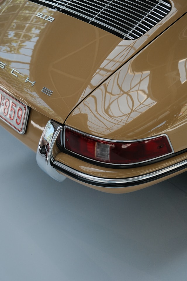 Gros plan sur le phare avant rond et l'aile d'une Porsche 912, mettant en valeur le style intemporel des premières Porsche.