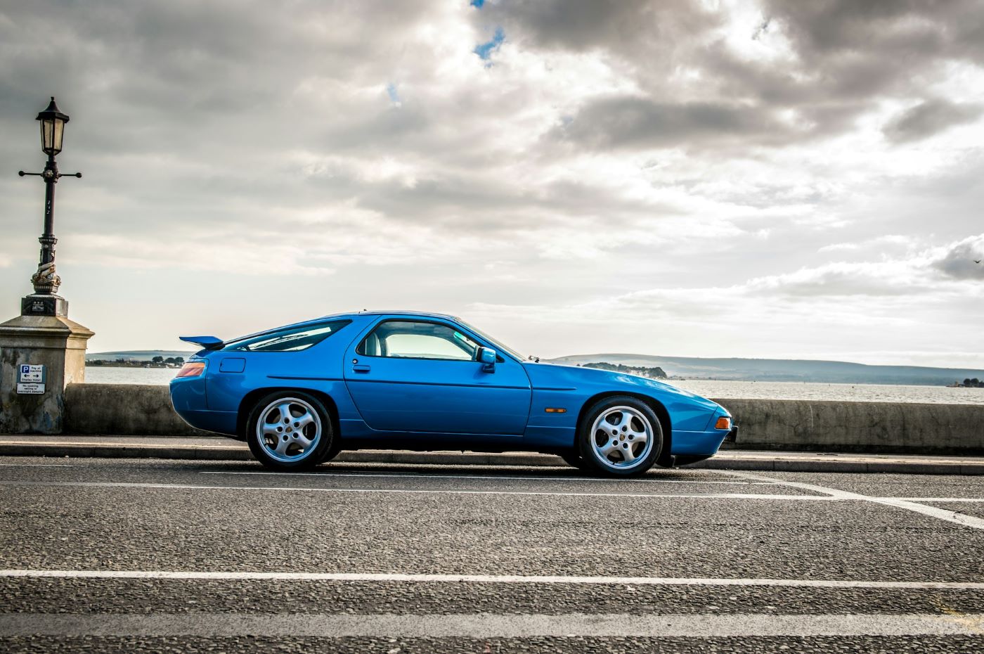 Profil d'une Porsche 928 de collection mettant en valeur sa silhouette caractéristique de Grand Tourisme et ses lignes typiques des années 1980.