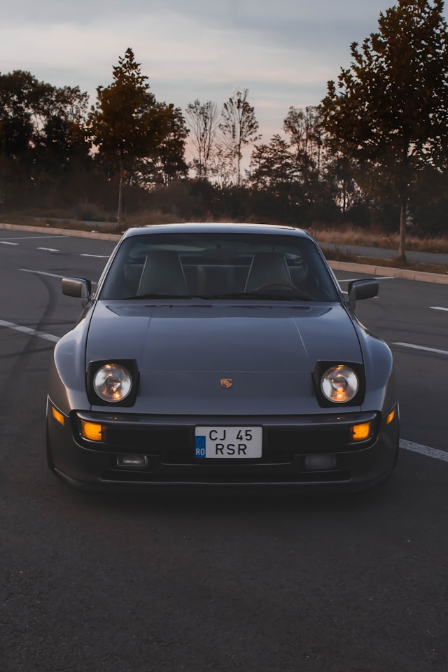 Conducteur au volant d'une Porsche 944 sur route sinueuse, illustrant le comportement routier équilibré et le plaisir de conduite du modèle.