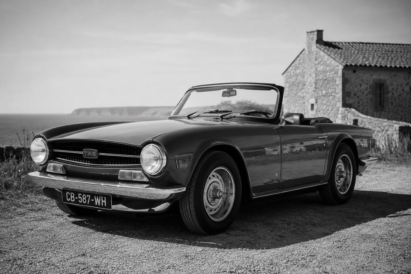 Photographie en noir et blanc d'une Triumph TR6 Cabriolet, évoquant les publicités et l'ambiance des roadsters britanniques des années 1970.