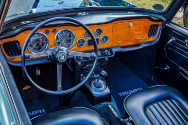 Tableau de bord en bois d'une Triumph TR4 avec instrumentation Smiths, volant trois branches et commandes d'origine.