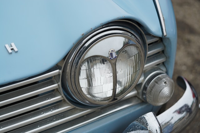 Gros plan sur le phare avant et la calandre chromée d'une Triumph TR4, détail caractéristique du design britannique des années 1960.
