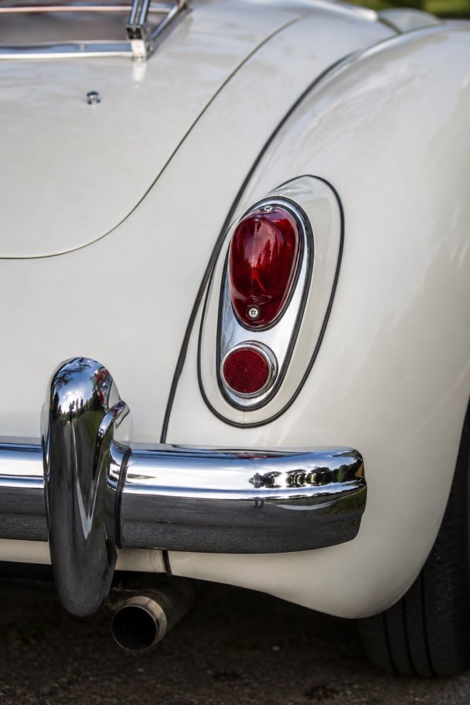 Gros plan sur le feu arrière droit et les chromes d'une MGA, mettant en valeur les détails de finition du roadster MG.