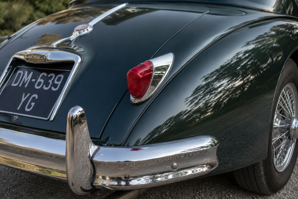 Gros plan sur le feu arrière droit et les chromes d'une Jaguar XK150, illustrant la qualité de finition des Jaguar classiques.