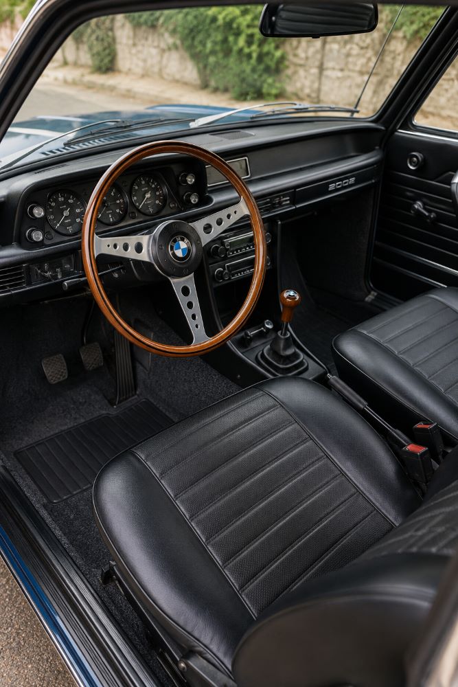 Habitacle d'une BMW 2002 avec volant d'origine, instrumentation VDO et boîte de vitesses manuelle.