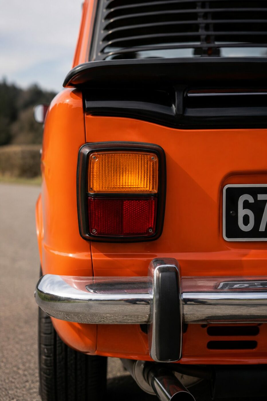  Gros plan sur le feu arrière iconique d'une Simca 1000 Rallye avec ses détails chromés.