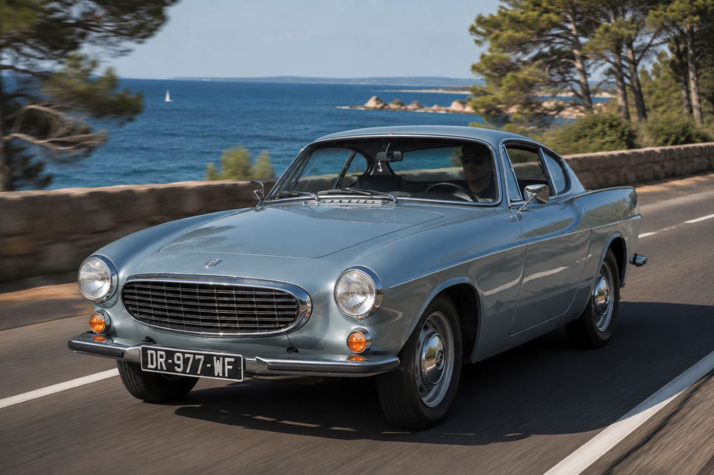 Volvo P1800 roulant sur une route côtière lors d'un essai routier en conditions réelles.