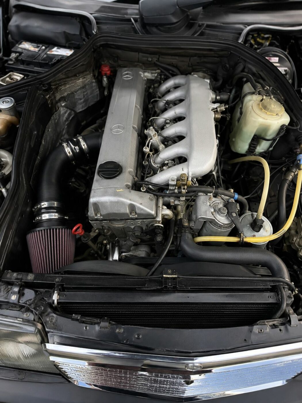  Vue verticale détaillée du compartiment moteur d'une Mercedes W124, illustrant la fiabilité et la qualité de fabrication.