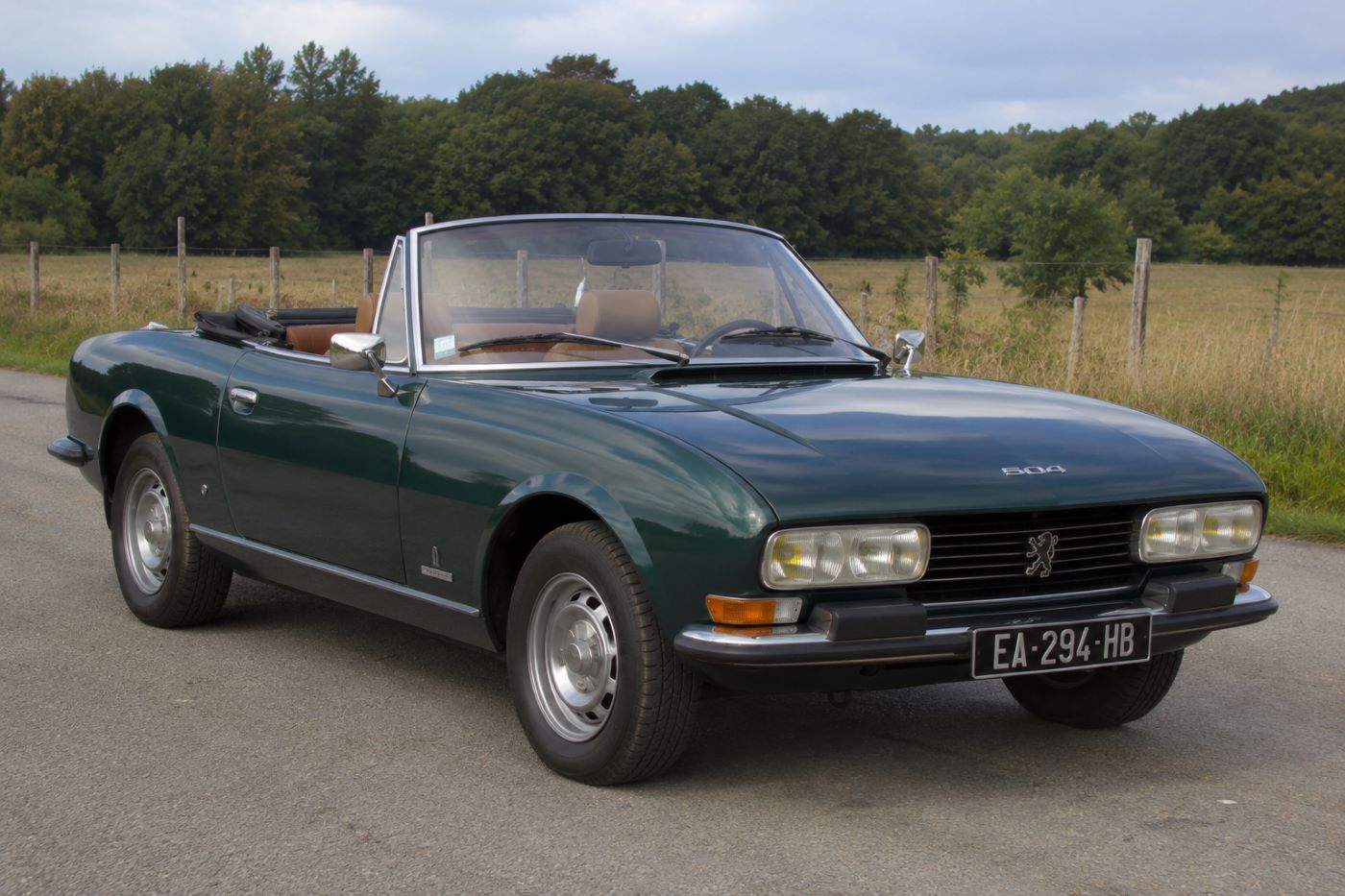 Peugeot 504 Cabriolet vue trois quarts avant bleu foncé sur une route de campagne