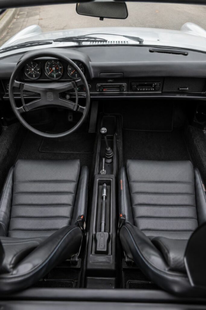 Habitacle d'origine d'une Porsche 914 avec tableau de bord orienté vers le conducteur, compteurs VDO et position de conduite sportive.