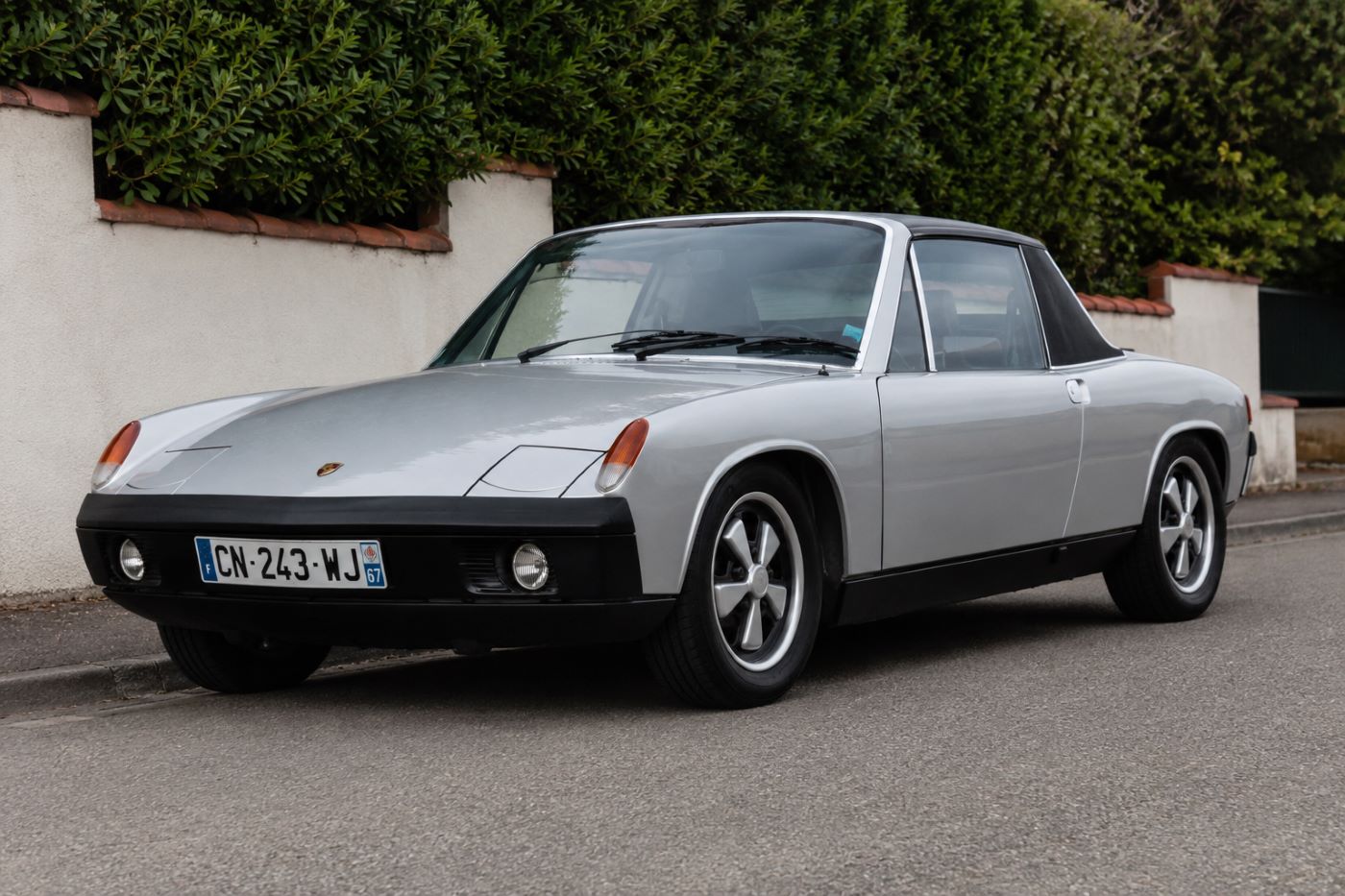 Porsche 914 jaune vue de trois quarts avant sur une route de campagne, mettant en valeur son design à moteur central et son toit Targa amovible