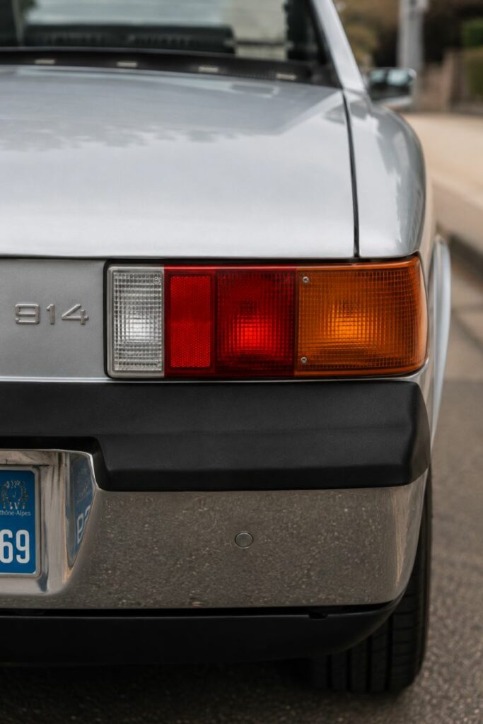 Zoom sur le logo Porsche et le bandeau arrière noir d'une Porsche 914, détail emblématique de ce roadster à moteur central.