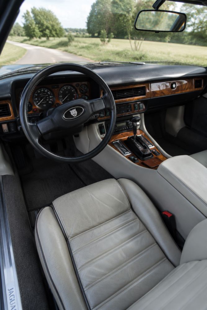 Habitacle d'origine d'une Jaguar XJS avec sellerie en cuir, boiseries et instrumentation typiques des GT britanniques des années 1980 et 1990, illustrant son niveau de confort et de raffinement.