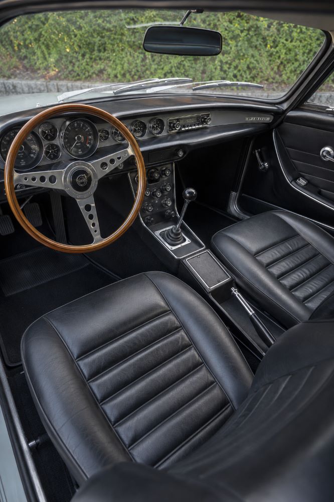 Habitacle d'une Volvo P1800 avec volant en bois, instrumentation d'origine et sellerie noire
