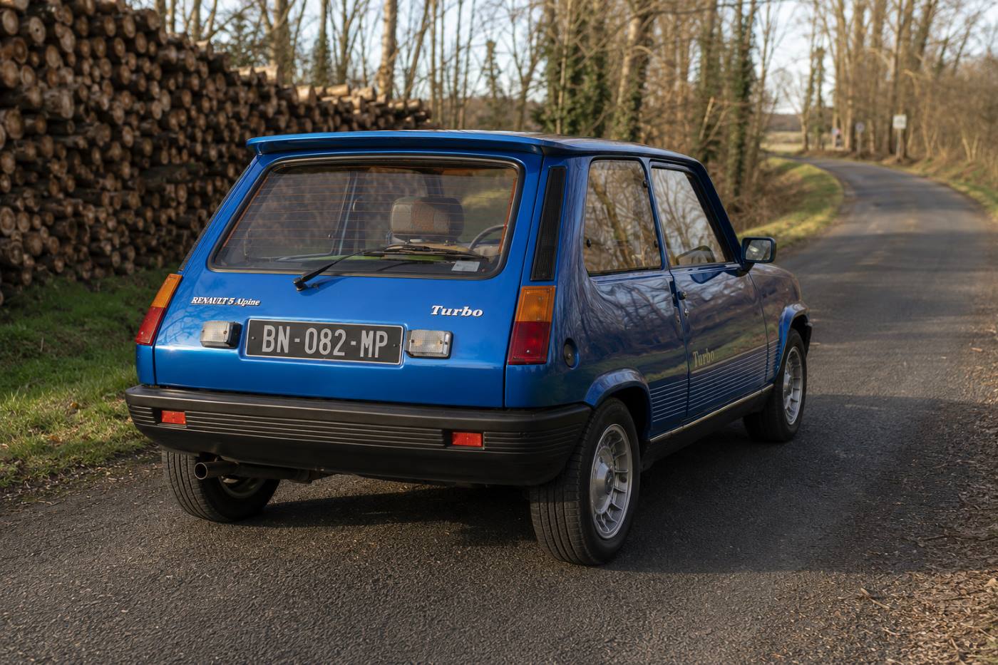 Vue de trois quarts arrière d’une Renault 5 Alpine Turbo, montrant son hayon, son becquet, ses feux arrière verticaux et les détails spécifiques de cette sportive française.