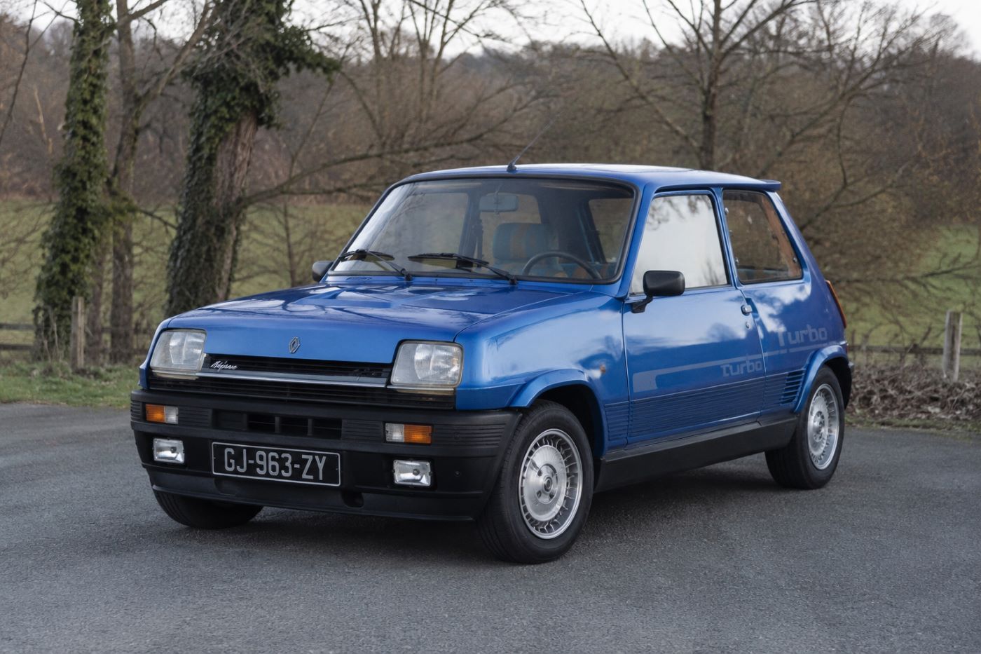 Renault 5 Alpine Turbo photographiée de trois quarts avant, mettant en valeur sa silhouette compacte, ses boucliers spécifiques, ses jantes Alpine et son style sportif typique des années 1980.
