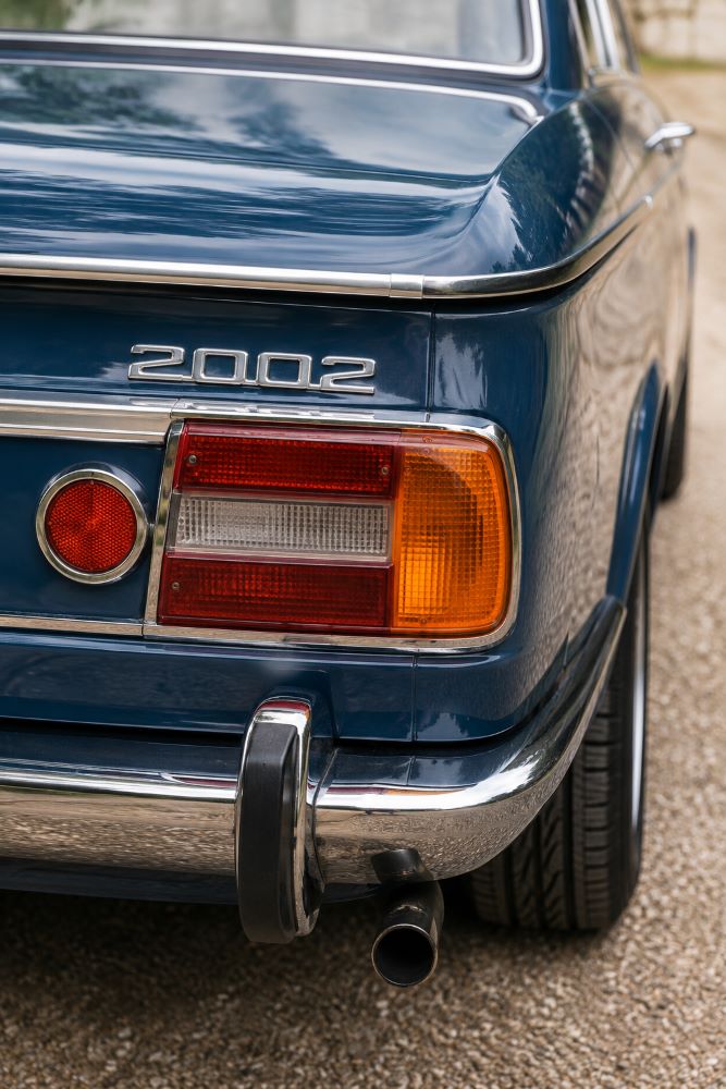 Gros plan sur le feu arrière droit et les chromes d'une BMW 2002 de collection.