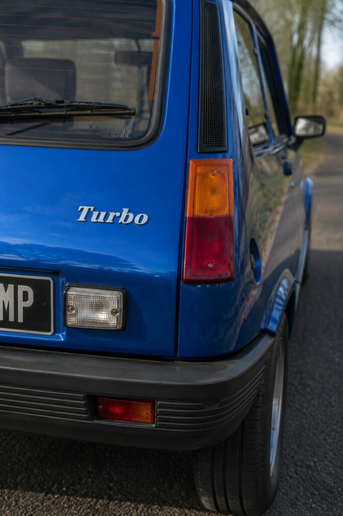 Gros plan sur le feu arrière droit d'une Renault 5 Alpine Turbo, mettant en valeur les optiques verticales, le hayon caractéristique et les détails de carrosserie propres à cette sportive française des années 1980