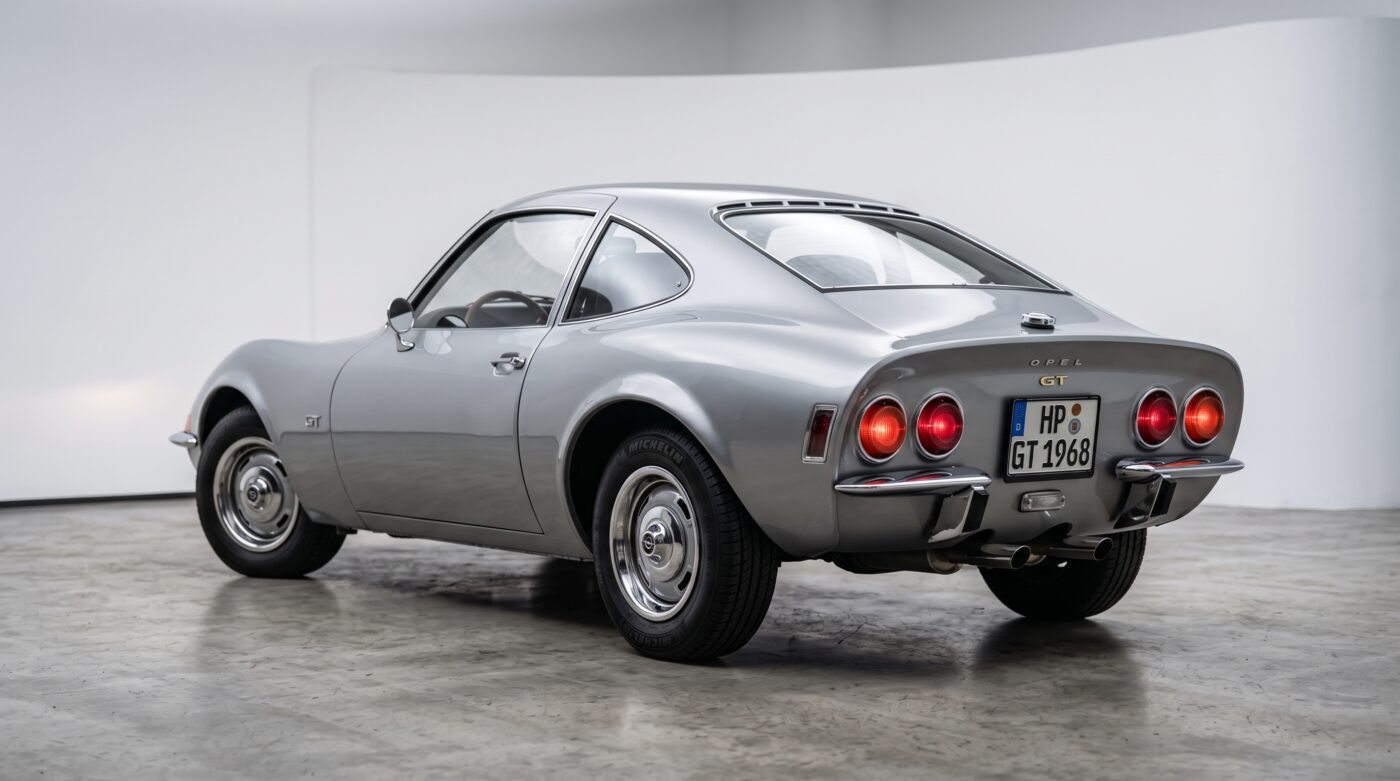 Vue de trois quarts arrière d'une Opel GT 1968 grise mettant en valeur ses lignes sportives et ses feux iconiques.