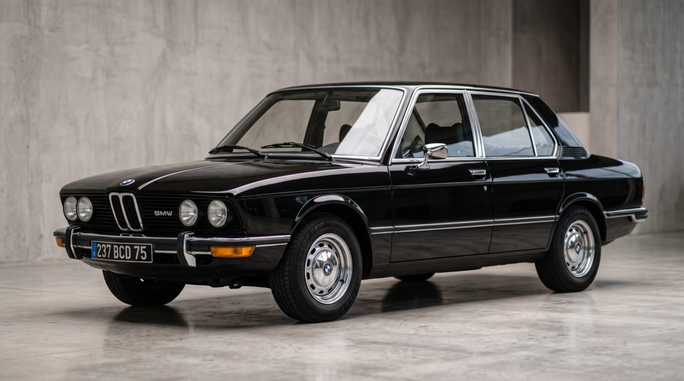 BMW E12 noire de 1972 vue de trois quarts avant, photographiée dans un style professionnel et élégant.