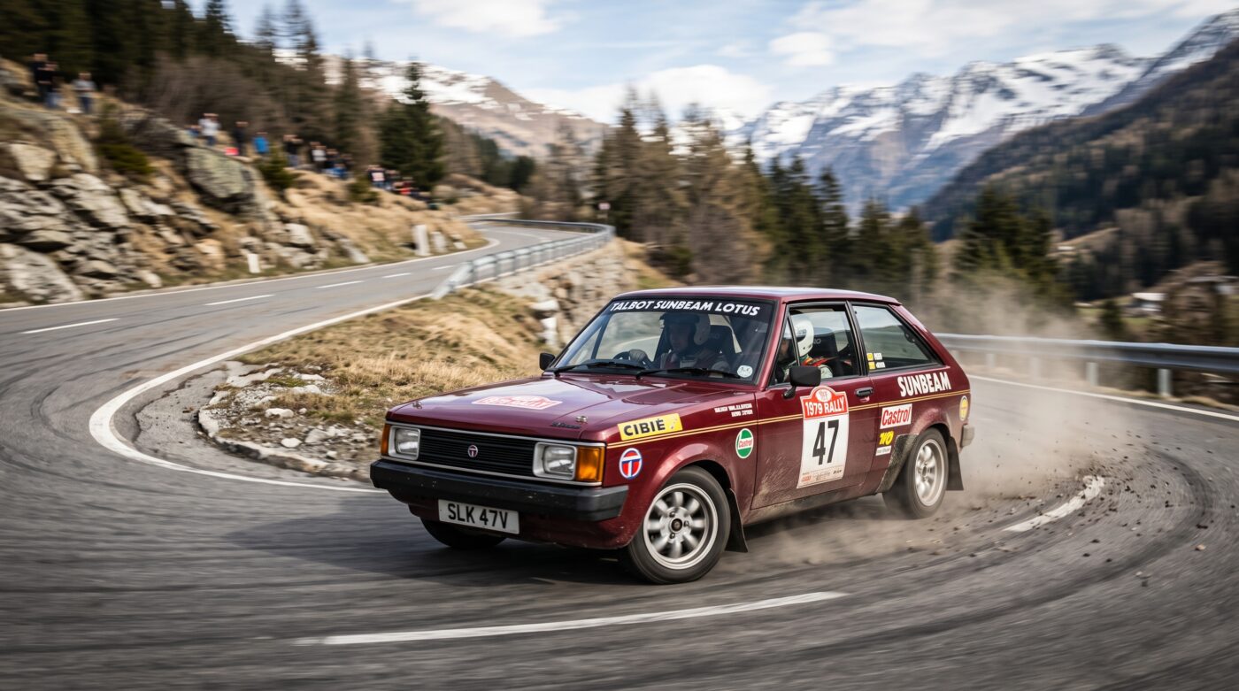 Talbot Sunbeam Lotus 1979 - Essai dynamique Essai routier d'une Talbot Sunbeam Lotus bordeaux en plein virage sur une route sinueuse.